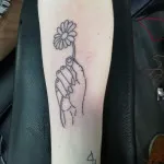 Hand holding a flower tattoo